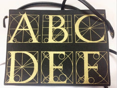 Vintage Paloma Picasso black canvas and leather combo shoulder bag with golden A B C D E F and S T V X Y letter print.