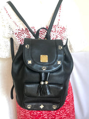 Vintage MCM black backpack with golden studded logo motifs and drawstrings. Designed by Michael Cromer. Unisex bag for daily use.