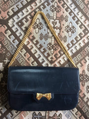 Vintage Nina Ricci navy leather clutch chain shoulder bag, classic purse with golden ribbon logo motif. Mod and chic daily purse.