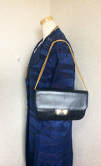 Vintage Nina Ricci navy leather clutch chain shoulder bag, classic purse with golden ribbon logo motif. Mod and chic daily purse.
